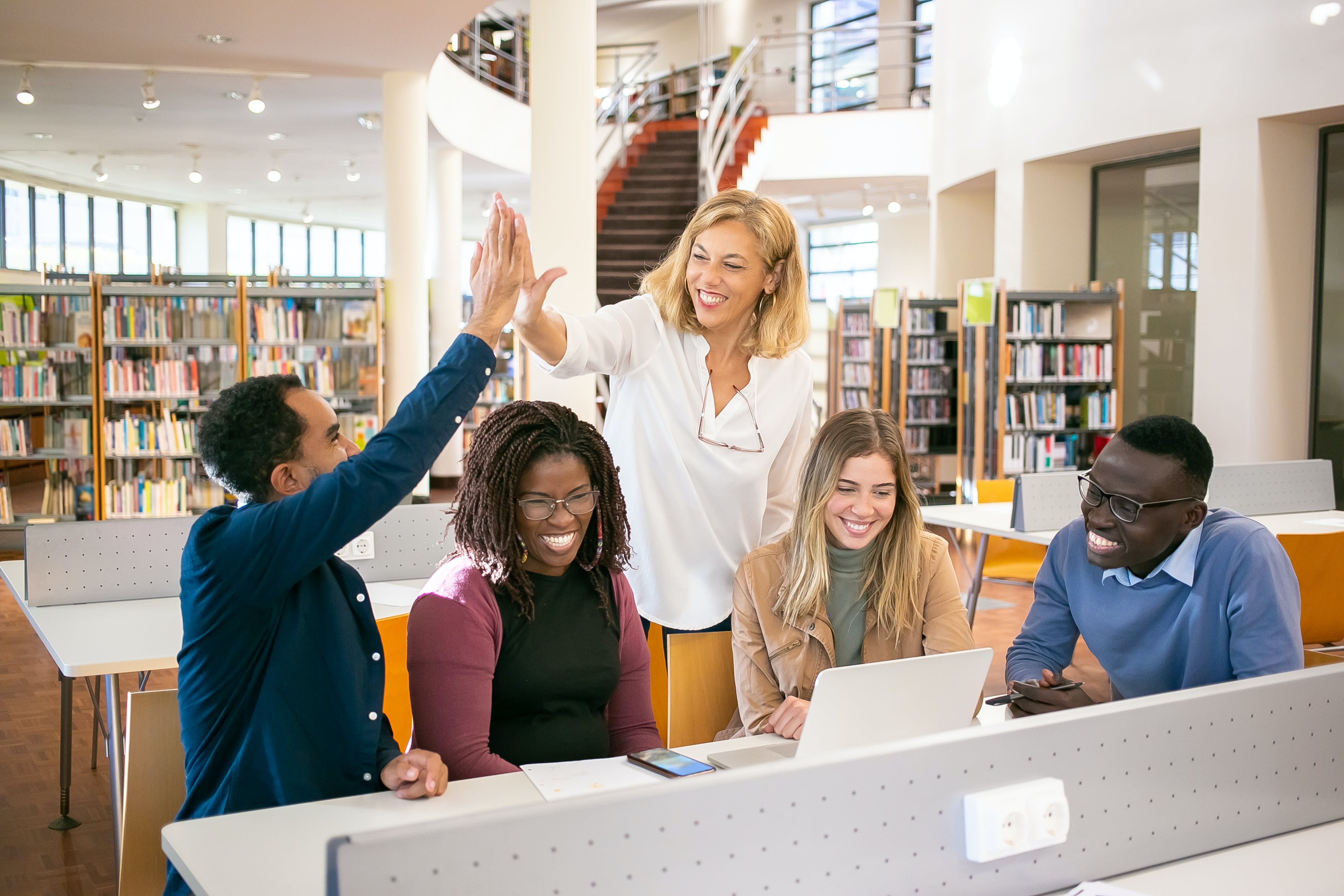 Free Cheerful multiethnic students having high five with teacher Stock Photo